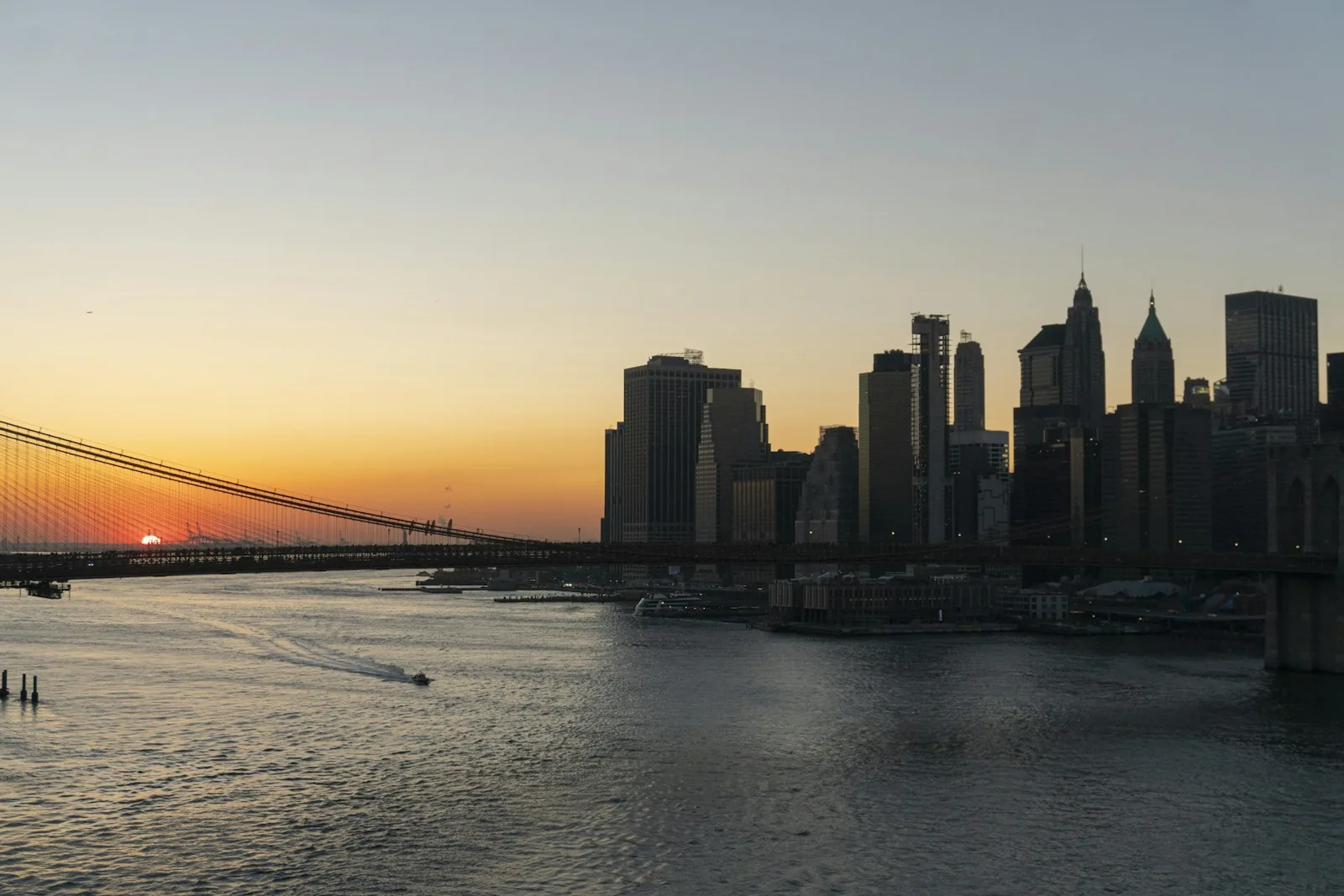 The Brooklyn Bridge and New York skyline in warm sunset light.