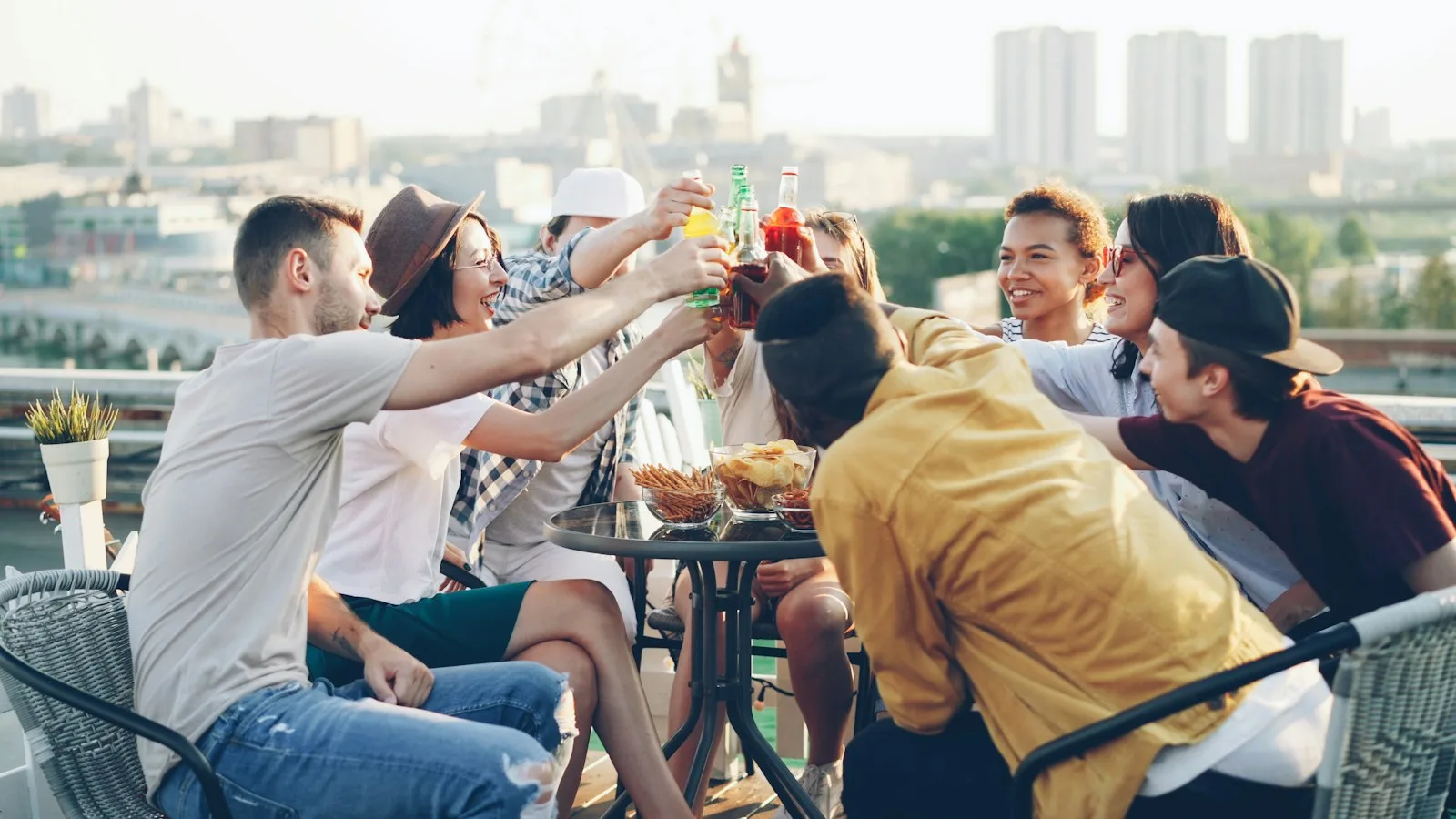 Friends sharing food and raising a toast together on a sunny city rooftop.